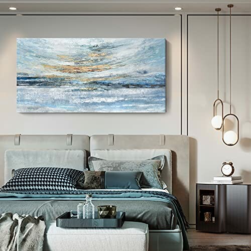 Modern bedroom with abstract seascape painting above bed.