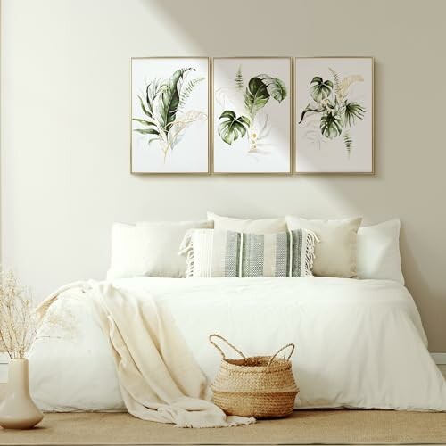 Minimalist bedroom with white bedding, framed plant artwork, and woven basket.