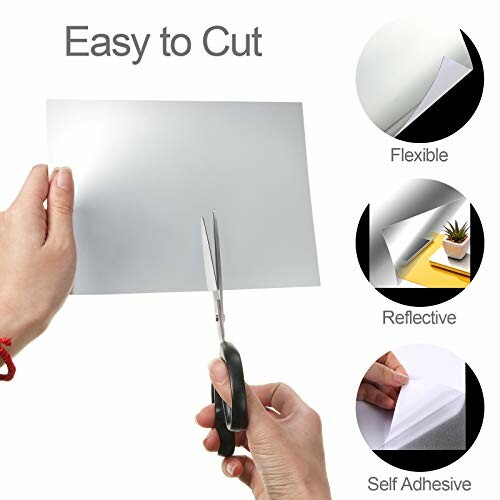 Hands cutting a flexible, reflective, self-adhesive sheet with scissors.