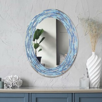 Oval mirror with blue mosaic frame above a blue cabinet.