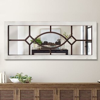 Decorative wall mirror with geometric design reflecting room interior.