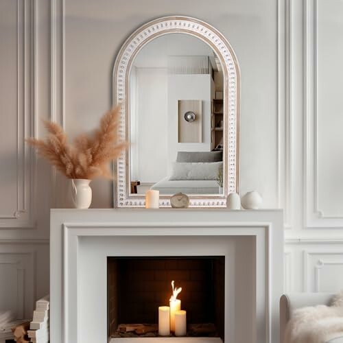 Stylish living room with a mirror above a fireplace, candles, and pampas grass