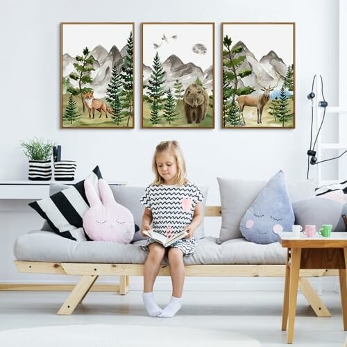 Girl reading on a sofa with forest-themed paintings above.