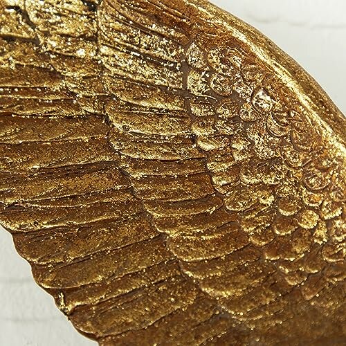 Close-up of a golden feather sculpture with textured details.