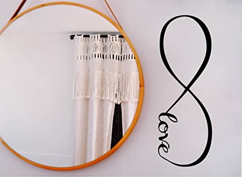 Round mirror reflecting curtains with an infinity love wall decal.