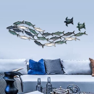 Metal fish and turtle wall art above a blue sofa with pillows.