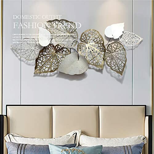 Decorative metal leaf wall art above a bed with pillows