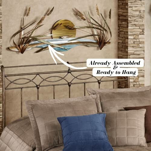 Metal wall art featuring a sun and waves above a bed with pillows.