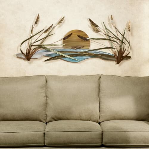 Metal wall art depicting sun and reeds above a green sofa.