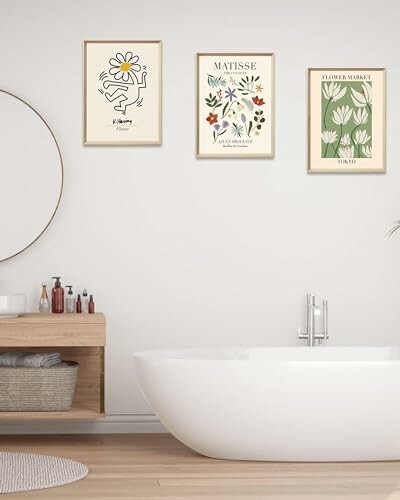 Minimalist bathroom with a round mirror and three framed art posters above a bathtub.