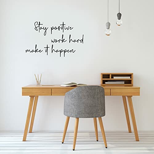 Minimalist desk with motivational wall quote and hanging lights.