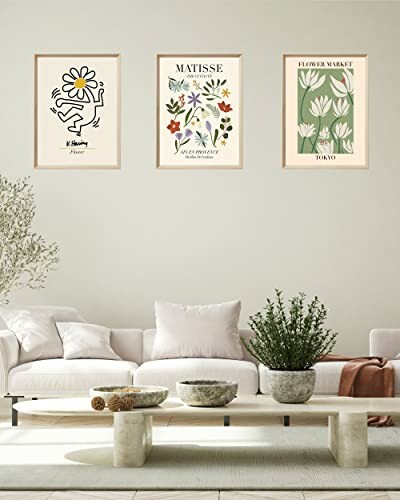 Living room with three framed floral artworks above a white sofa and plants.