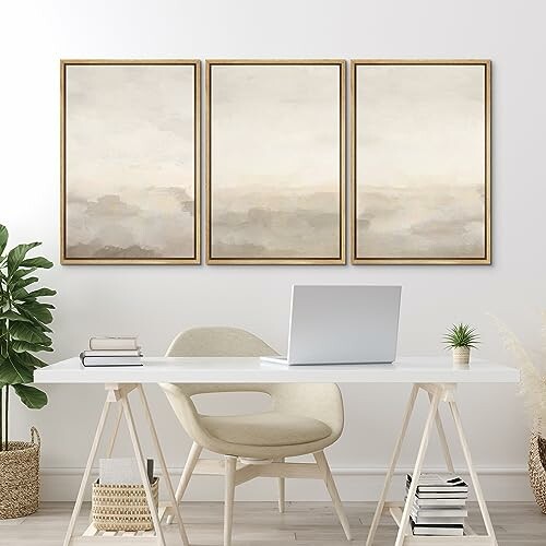 Minimalist office with abstract art and laptop on desk.