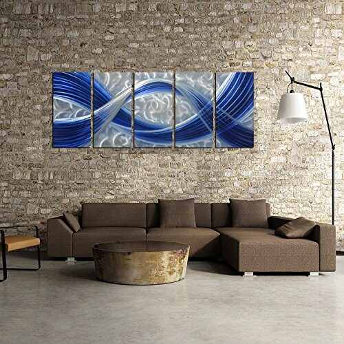 Modern abstract wall art above a brown sectional sofa with a round coffee table in a brick-walled living room.