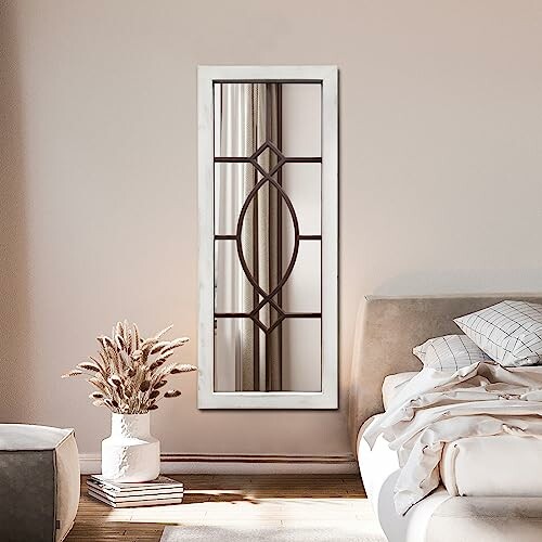 Elegant wall mirror in a modern bedroom with a bed and decorative vase.