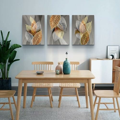 Modern dining room with wooden table, chairs, and leaf art on the wall.