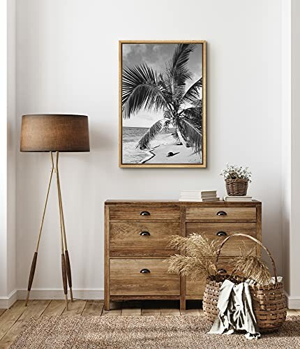 Modern interior with a wooden dresser, floor lamp, and framed beach photo.