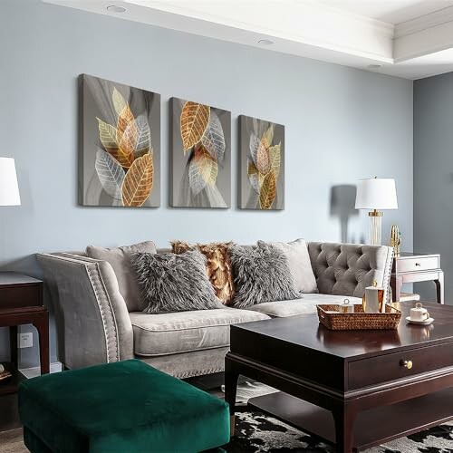 Modern living room with gray sofa, leaf artwork, and dark wood coffee table.