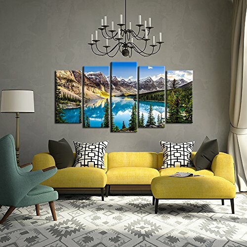 Modern living room with yellow sofa, armchairs, and mountain landscape painting.