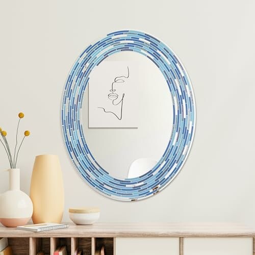 Oval mirror with blue mosaic frame on a wall above a table with vases.