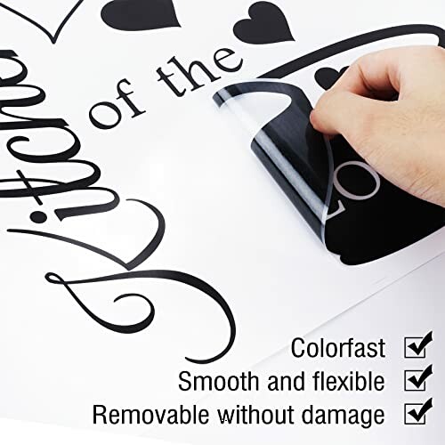 Hand peeling wall decal with text and heart design.