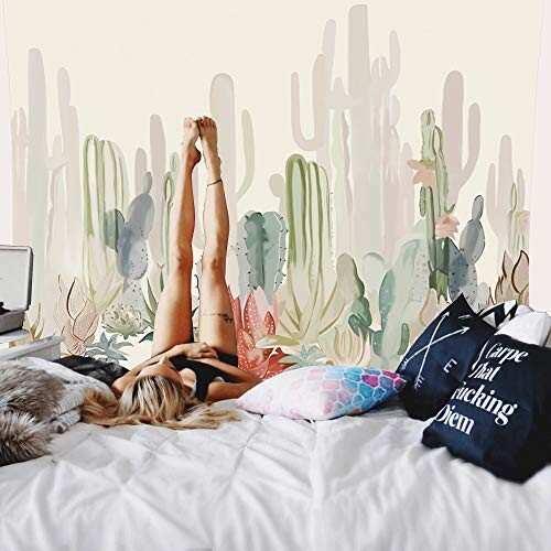 Woman lying on bed with legs up, cactus wall art in background.